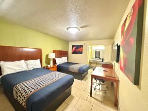 a hotel room with two beds and a desk at Texas Inn Beaumont in Beaumont