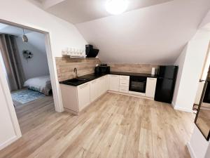 a kitchen with white cabinets and a black appliances at Apartament Storczykowy in Frombork