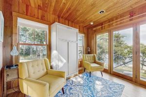 a living room with two chairs and a refrigerator at Waterfront Paradise with Dock, Big Yard, Sundeck & Epic Bay Views | Dog-Friendly in Boothbay