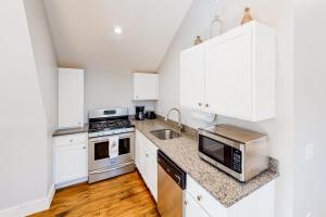 a kitchen with white cabinets and a sink and a microwave at Cozy and modern hideaway - walk to the beach - fast WiFi & washer/dryer in Marlboro