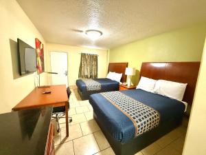 a hotel room with two beds and a desk at Texas Inn Beaumont in Beaumont