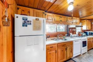 a kitchen with a white refrigerator and wooden cabinets at Vintage lakefront cabin with incredible water views, private dock & pebble beach in The Highlands