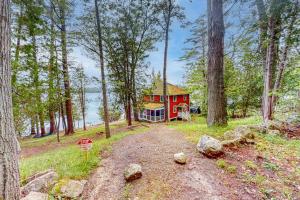 a red house in the middle of a forest at Cozy, Waterfront Cabin-Style Gem with Private Dock and Lovely Views in East Harpswell
