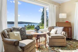 a living room with two chairs and a large window at Dog-friendly oceanfront home with private shorefront, two fireplaces, & firepit in Steuben