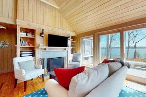 a living room with a couch and a fireplace at Oceanfront retreat with sunrise views, screened porch, & deck in Blue Hill