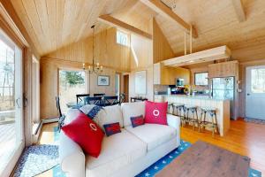 a living room with a white couch and a kitchen at Oceanfront retreat with sunrise views, screened porch, & deck in Blue Hill