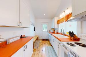 a kitchen with white cabinets and orange counter tops at Waterfront home on St George River with private beach & deck - near festivals in Cushing
