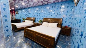 two beds in a room with blue wallpaper at The Al-Maaz Guest House in Murree