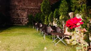 a row of chairs and a table with a bouquet of red flowers at The Al-Maaz Guest House in Murree