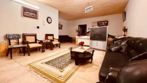 a living room with a leather couch and a tv at The Al-Maaz Guest House in Murree