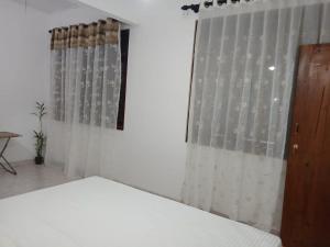 a bedroom with a bed and a window with curtains at The Emerald Ceylon - Colombo in Pannipitiya