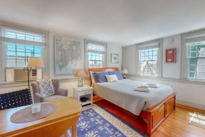 a bedroom with a bed and a chair and windows at Lovely studio w/full kitchen/free WiFi- next to river/antique shops/restaurants in Wiscasset