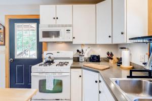 a kitchen with white cabinets and a stove and a sink at Two-story home steps from Laite Beach - stroll to the harbor, 1 dog welcome in Camden