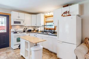 a kitchen with white cabinets and a white refrigerator at Two-story home steps from Laite Beach - stroll to the harbor, 1 dog welcome in Camden