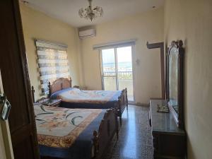 a bedroom with two beds and a mirror and a window at Super sea promenade apartment in El Mîna