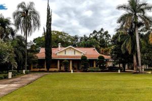 a house with palm trees in front of a yard at Private Suite with Kitchen & Pool Access in Itapetininga