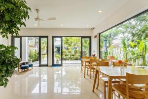 a dining room with tables and chairs and large windows at Buddy January Villa in Hoi An