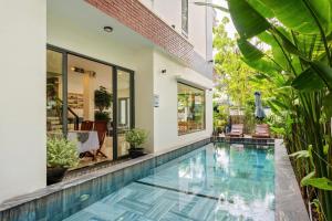 a swimming pool in front of a house with plants at Buddy January Villa in Hoi An