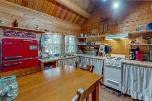 a kitchen with a red stove and a wooden table at The Cottage - Peaceful 32-Acre Lakefront Getaway - Canoe, Firepit & Big Deck in Franklin