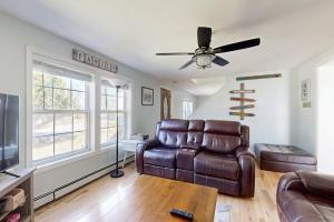 a living room with a couch and a ceiling fan at Dog-friendly home with deck, pool table, & firepit - walk to downtown Boothbay in Boothbay Harbor