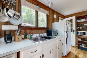 a kitchen with a sink and a refrigerator at Lady Slipper Cottage: Charming Lakefront Retreat with Canoes, Kayaks, and Modern Comforts in Somesville