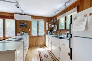 a kitchen with white appliances and wooden walls at Lady Slipper Cottage: Charming Lakefront Retreat with Canoes, Kayaks, and Modern Comforts in Somesville