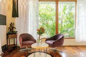 two chairs and a table in a room with a window at Ocho Artisan Bungalows in Tamarindo