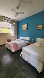 a bedroom with two beds and a blue wall at Pousada Morada do Tombo in Guarujá