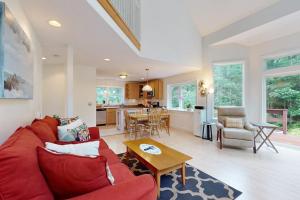 a living room with a red couch and a table at Sunny coastal retreat with deck, grill, beach, dock, & ocean access in East Boothbay