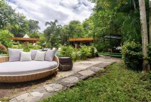 a wicker couch sitting on a path in a garden at Ocho Artisan Bungalows in Tamarindo