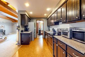 a large kitchen with wooden cabinets and stainless steel appliances at Tree-lined home with screened porch & perfect Midcoast location in Damariscotta +14 photos