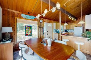 a kitchen with a wooden table and white chairs at Stunning artist's retreat with ocean view & amazing deck, near Reid State Park in Georgetown +22 photos