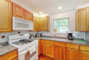 a kitchen with wooden cabinets and a white stove top oven at Secluded lakefront home with patio & firepit, fast WiFi, wood stove & W/D in Ellsworth