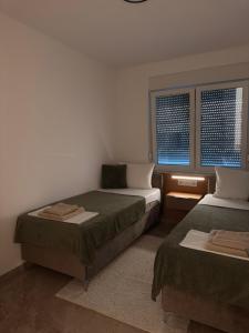 a bedroom with two beds and two windows at Villa Una Bellevue in Bihać