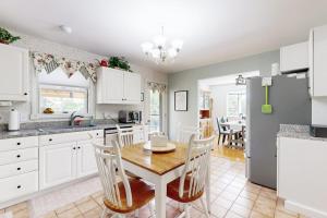 a kitchen with white cabinets and a table and chairs at Charming Lakefront House with Outdoor Firepit, Washer/Dryer and Wifi in Gouldsboro +21 photos