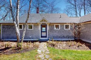 a home with a blue house with a door at Oceanfront retreat with sunrise views, screened porch, & deck in Blue Hill