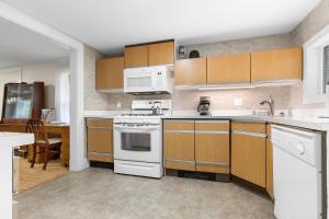a kitchen with white appliances and wooden cabinets at Bright, spacious getaway with full kitchen, furnished porch & WiFi - near trails in Seal Harbor