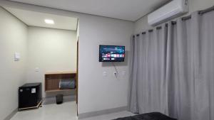a room with a tv on a wall with curtains at Pousada Vila dos Anjos in Chapada dos Guimarães