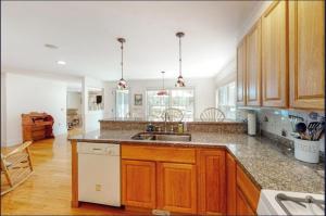 a large kitchen with wooden cabinets and a sink at Secluded lakefront home with patio & firepit, fast WiFi, wood stove & W/D in Ellsworth +24 photos
