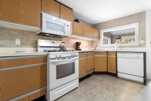 a kitchen with white appliances and wooden cabinets at Bright, spacious getaway with full kitchen, furnished porch & WiFi - near trails in Seal Harbor