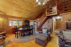 a living room with a table and chairs and a staircase at Lakefront Home with Private Dock, Pebble Beach & Enclosed Porch - Dogs Welcome in Greenville Junction +23 photos