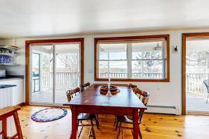 a dining room with a wooden table and windows at Dog-friendly river-view home with wood stove, deck, patio, dock, beach, grill in Boothbay