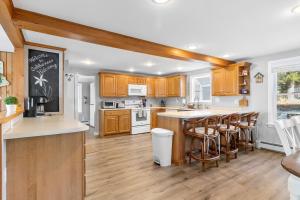 a kitchen with wooden cabinets and a counter with bar stools at Cobbossee Hideaway, lakefront property with dock for swimming, fishing, and sunrises in Winthrop