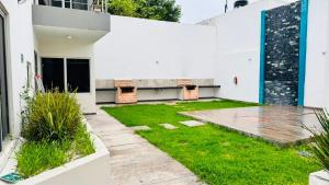 a courtyard of a white house with a lawn at Departamento moderno en Durango in Durango