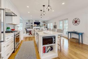 a kitchen with white cabinets and a island with a microwave at Elegant home with veranda & water view, walk to downtown Boothbay Harbor in Boothbay Harbor