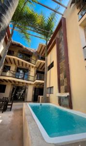 a swimming pool in front of a building with palm trees at Jardín del Mar by ÓOL Hotels in Holbox Island