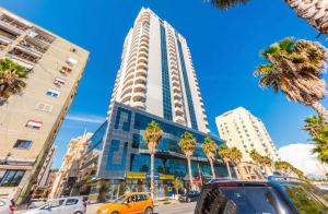 a tall building with palm trees in front of it at Via Mare Jacuzzi Suites by PS in Durrës