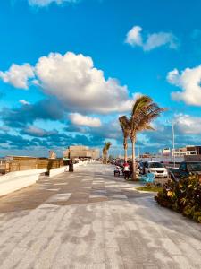 a street with palm trees and a blue sky at Casa Corazón de Boca, steps from the beach and restaurants in Boca del Río