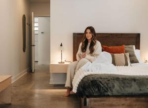 a woman sitting on a bed in a bedroom at Chalet Gratitude with Private SPA & Sauna in Saint Come
