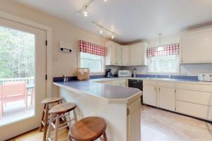 a kitchen with white cabinets and a counter with stools at Home with deck, great location in the heart of Acadia National Park in Otter Creek +19 photos